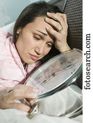 Woman laying in bed with giant alarm clock