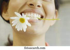 Woman smiling with flower in her teeth