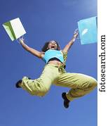Low angle view of African woman jumping with shopping bags