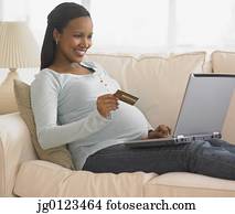 Pregnant African woman shopping online on sofa