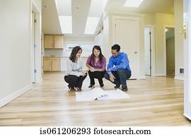 Asian couple looking at blueprints in new house