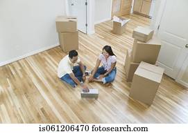 Asian couple looking at laptop in new house 