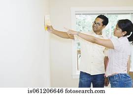 Asian couple looking at paint swatches in new house