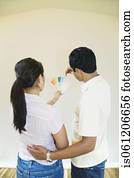 Asian couple looking at paint swatches in new house