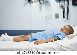 African boy in hospital bed with blood pressure cuff 