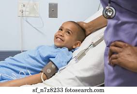 African boy smiling at nurse in hospital bed