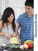 Asian couple chopping vegetables in kitchen