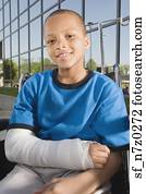 Close up of African boy with broken arm in wheelchair outdoors