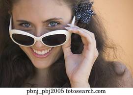 Close up of young woman smiling over top of sunglasses