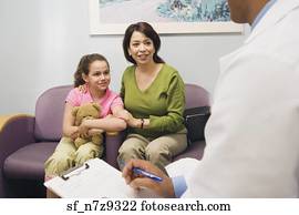 Doctor talking to Hispanic mother and daughter in waiting room