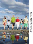 Hispanic family holding hands and walking on beach