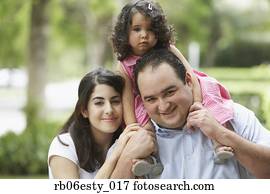 Hispanic father and mother with daughter on shoulders