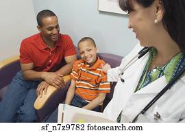 Hispanic female doctor smiling at African father and son in waiting room