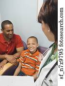 Hispanic female doctor talking to African father and son in waiting room
