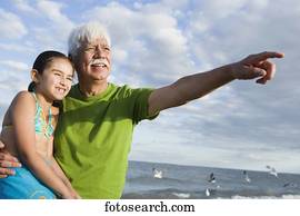 Hispanic grandfather with granddaughter pointing into the distance