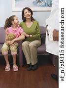 Hispanic mother and daughter talking to doctor in waiting room