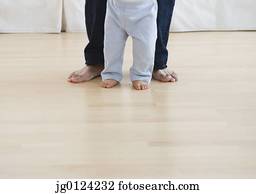 Low section of barefoot baby and father