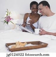 Middle-aged African couple having breakfast in bed