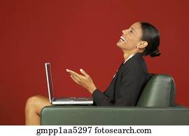 Profile of African businesswoman laughing with laptop in armchair