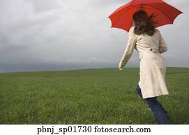 Rear view of woman running with umbrella in field