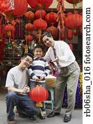 Asian grandfather, father and son in front of lantern shop