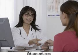 Female doctor handing prescription to patient