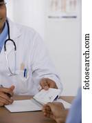 Male doctor handing prescription to patient