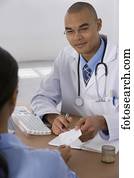 Male doctor handing prescription to patient