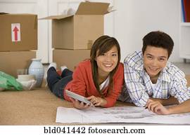 Asian couple looking at blueprints in new house