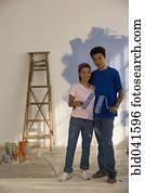 Asian couple painting interior of house