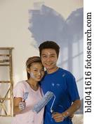 Asian couple painting interior of house