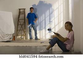 Asian couple painting interior of house