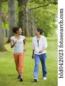 African American mother and adult daughter walking in park