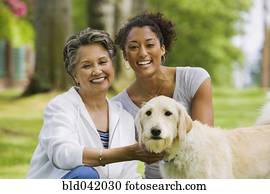 African American mother and adult daughter petting dog