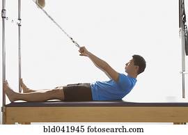 Asian man stretching on exercise equipment