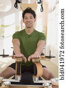 Asian man stretching on exercise equipment