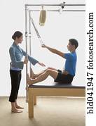 Instructor helping man on exercise equipment