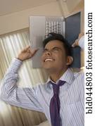 Hispanic businessman holding laptop around head
