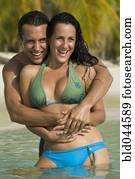 Hispanic couple hugging in water