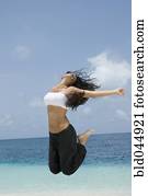 Hispanic woman jumping at beach
