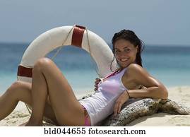 Young woman holding life preserver at beach