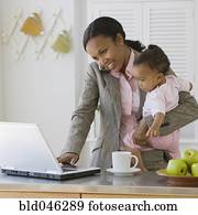 African American mother working at holding baby