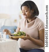 Pregnant African American woman eating salad