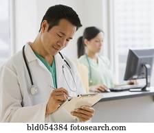 Asian male doctor writing on chart
