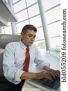 Hispanic businessman typing on laptop