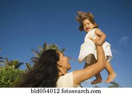 Pacific Islander mother holding daughter in air
