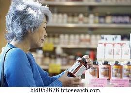 Senior Asian woman reading vitamin label
