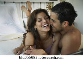 Hispanic couple laughing on bed Hispanic couple laughing on bed