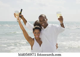 Multi-ethnic couple holding wine at beach