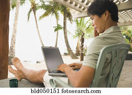 Asian man typing on laptop